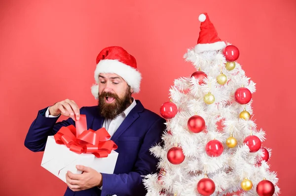 Gifts shop. Christmas gifts. Winter holidays. Boxing day. Christmas party. Sharing kindness and happiness. Prepare gifts for everyone. Man bearded hipster formal suit christmas tree hold gift box.