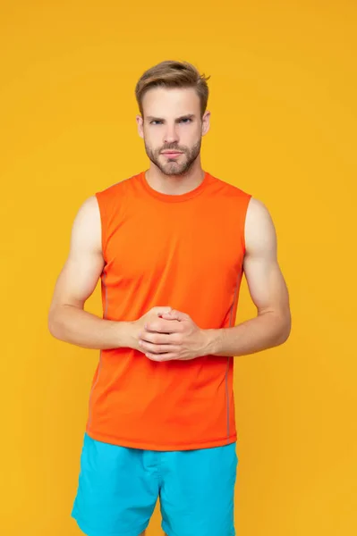 Serious athlete isolated on yellow. Athletic guy studio. Sporting guy in sportswear. Fitness and sport. Athletic fitness. Sport and recreational activity.