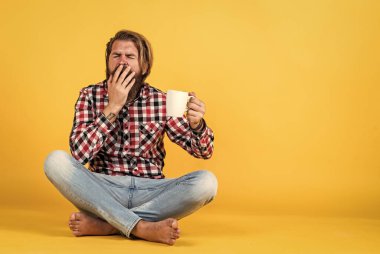 Uykulu, yorgun adam. O bir kahve molası veriyor. Fincandan su içen yakışıklı bir yetişkin. Bir fincan kahve ya da çay. Yaşam tarzı konsepti. Kahveli yakışıklı hippi..