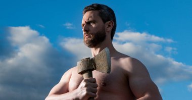 Baltalı üstsüz adam. Beyaz adam, baltayı tut. Arka planda vahşi bir adam. güçlü pazılar..