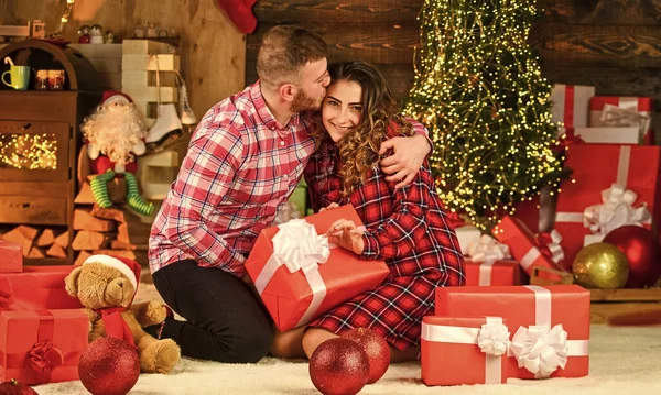 Christmas shopping idea. romantic couple is having fun. evening before xmas. Enjoying spending time together in New Year Eve. Couple in love sit next to Christmas tree. hugging among present boxes.