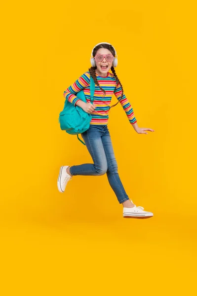 快乐精力充沛的少女放学后跳出黄色的背景 回学校去 — 图库照片