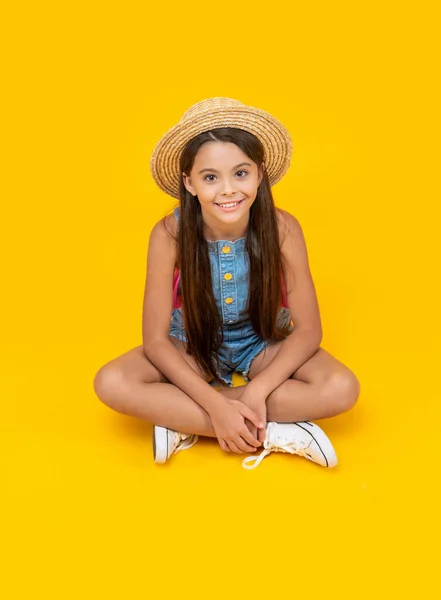 戴着草帽坐在黄色背景上的快乐少女 — 图库照片