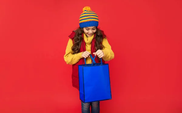 kid with package. happy birthday holiday. black friday discount. seasonal christmas sales. cheerful teen girl in open shopping bag. present and gifts buy. shopping child with purchase.