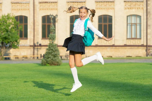 兴奋的女生在半空中跳 在学校 精力充沛的少女背着书包 回学校去 — 图库照片
