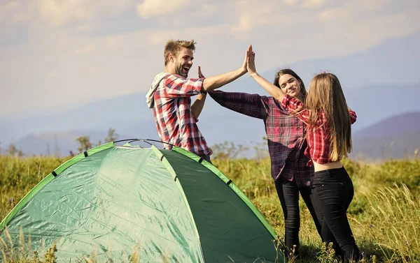 Total relaxation. friends camping. reach destination place. group of people spend time together. man and two girls pitch tent. wanderlust discovery. hiking outdoor adventure. mountain tourism camp.