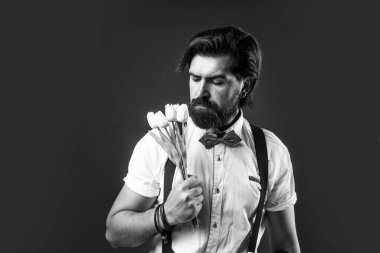 Bahar çiçeği hediyesi. Askılı ve papyonlu romantik bir adam. Kendine güvenen ve zarif bir adam lale çiçekleri tutar. Aşk randevusu için hediye. Buketli eski moda sakallı hippi..