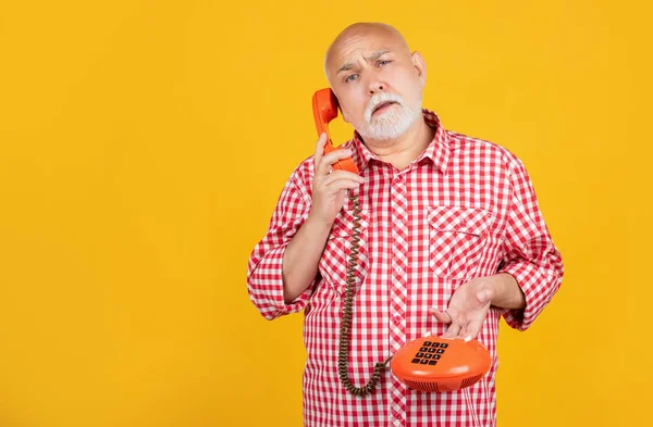 Przemyślany Starszy Mężczyzna Telefonem Retro Żółtym Tle — Zdjęcie stockowe