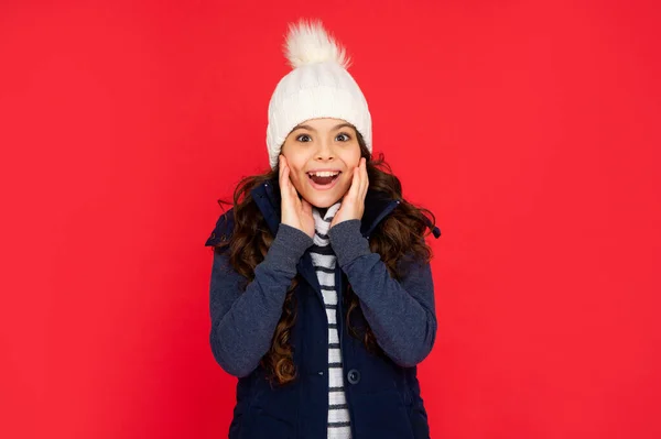 肯定的な感情を表現する 冬のファッション 気持ちのいい子供が帽子をかぶってる 赤を背景に10代の女の子 暖かい服を着た子供の肖像画 — ストック写真