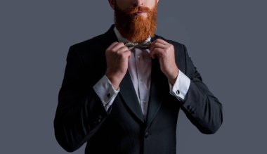 Sakallı, şık görünümlü şık bir adam gri renkli, şık bir papyon stüdyosu ayarlıyor. Smokin tarzı. Resmi biçim.