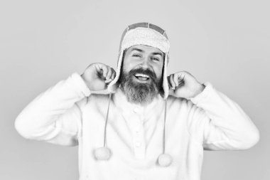 Neşeli hissediyorum. Sonbahar hava tahmini. Kulak şapkası soğuktan korur. Sakallı adam kış şapkası takıyor. Soğuk hava için moda giysileri. Olgun hippi sarı arka plan. erkek modası.