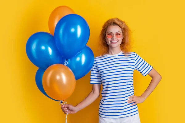 caucasian woman with birthday balloon in sunglasses. happy birthday woman hold party balloons in studio. woman with balloon for birthday party isolated on yellow background.