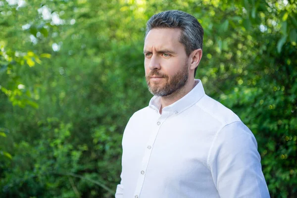 Beyaz gömlekli yakışıklı profesyonel adam. Doğal arka plan, kopyalama alanı..