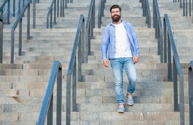 Sakallı adam aşağı iniyor. Sakallı bir adam. Merdivenlerde hippi bir adam var..