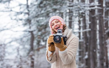 Gününü dışarıda geçir. Karlı doğada klasik kamerası olan bir kız. Seyahat konsepti. Kışın yakalanması. Çarpıcı kış fotoğrafları çek. Kış hobisi. Kadın fotoğrafçı. İlham özel bir şey yaratır..