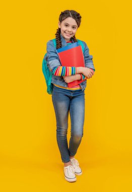 Mutlu kız okula geri döndü. Elinde kitap tutan ergen bir kız. Sarı arka planda gülümseyen genç kız. 1 Eylül. Bilgi günü.