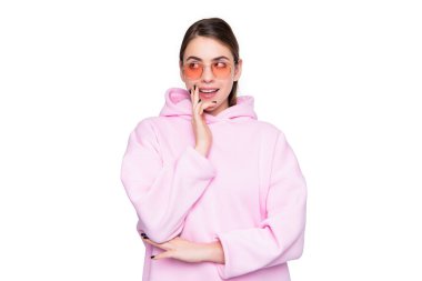 Düşünceli genç bir kadın parmaklarını pembe kapüşonlu ve beyaz gözlüklü çenesinde tutmayı düşünüyor..