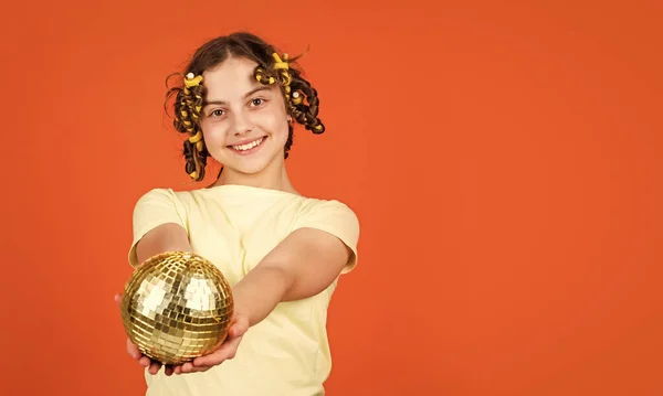 Fancy teen. Hairstyle for disco party. Have fun. Retro party. Child hold golden disco ball. Cheerful girl with disco ball. Fashion kid posing with curlers in hair. Night club. Hairdresser salon.