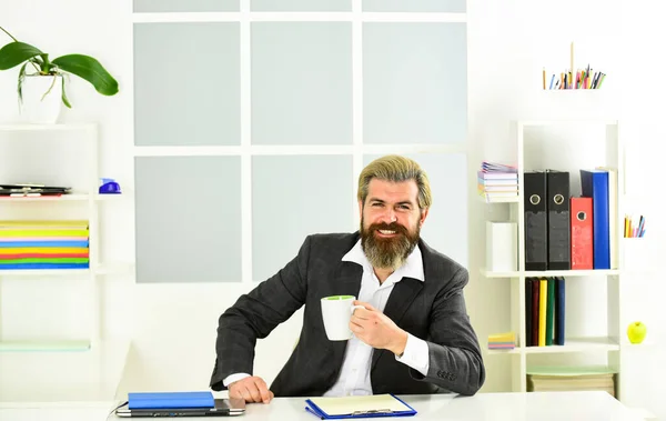 Man handsome boss sit in office drinking coffee. Bearded hipster formal suit relaxing with coffee. Inspired and motivated. Morning coffee in office. Office life. Good coffee. Respectable ceo.