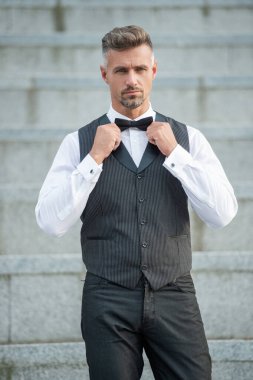 Papyonlu, olgun, zarif bir adam. Resmi giysili, kır saçlı bir adam. Smokinci damat..