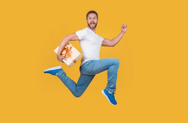 空中黄色のスタジオの背景にギフト宅配便 ギフトボックスで速く走る精力的な男 プレゼント ギフト配送 — ストック写真