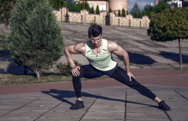 Güneşli yaz gün açık havada üzerinde eğitim atlet. Spor ve fitness. Maço eşofman kentsel peyzaj üzerinde uygun. Sağlıklı yaşam konsepti. Kasları egzersiz önce ısınma ve germe adam.