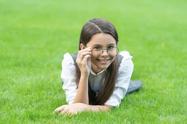 一个快乐的小女孩放学后在草地上调整眼镜的画像 面带微笑的少女 — 图库照片