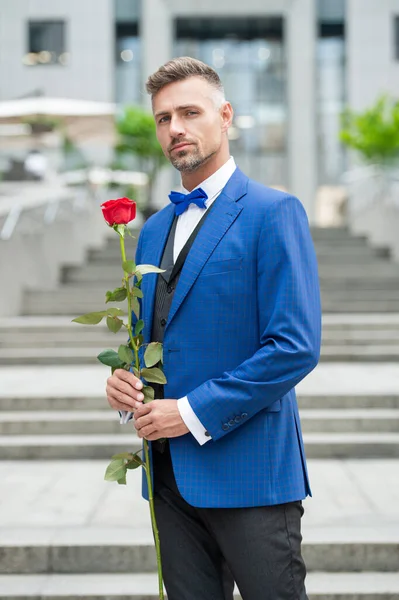 在浪漫的场合穿燕尾服的优雅男人 带着浪漫礼物的男人 俊俏的浪漫男人牵着玫瑰 — 图库照片