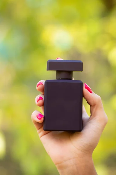 black perfume bottle in hand. presenting perfume bottle. presenting beauty product of perfume, copy space.