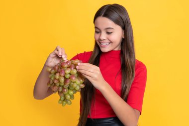 Mutlu çocuk sarı arka planda taze üzüm tutar..