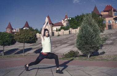 Kasları egzersiz önce ısınma ve germe adam. Maço eşofman kentsel peyzaj üzerinde uygun. Sağlıklı yaşam konsepti. Spor ve fitness. Güneşli yaz gün açık havada üzerinde eğitim atlet.