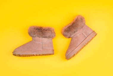 Ayakkabı dükkanı. Alışveriş konsepti. Kadın derisi şık ayakkabılar. Bir çift şık deri ugg bot. Sarı arka planda bilek çizmeleri.