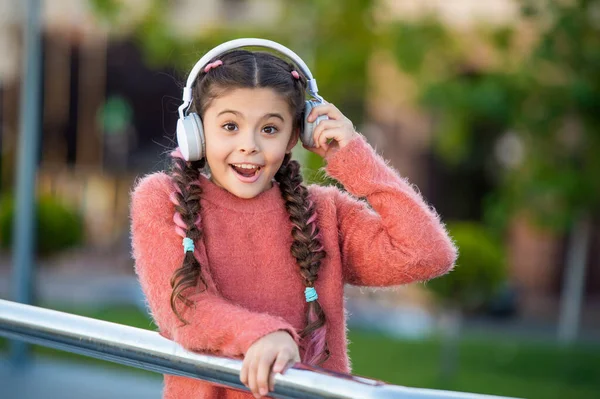 音楽のためにヘッドフォンを外してショックを受けた少女 十代の若者は耳の隣にヘッドフォンを保持します 衝撃を聞いて 音楽的な驚きだ — ストック写真