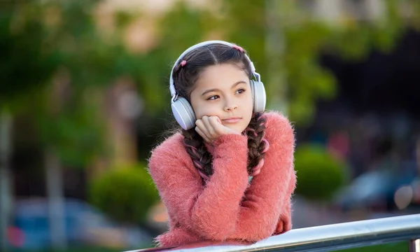 十代の女の子の手すりにもたれて考えて考えている 屋外で音楽を聴きながら考える10代の若者 — ストック写真