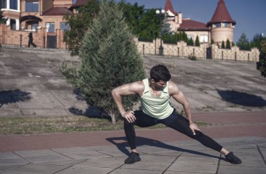 Maço eşofman kentsel peyzaj üzerinde uygun. Güneşli yaz gün açık havada üzerinde eğitim atlet. Spor ve fitness. Sağlıklı yaşam konsepti. Kasları egzersiz önce ısınma ve germe adam.