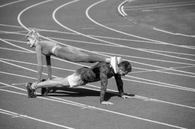 Kasları şişiriyorum. Atletik erkek ve kadın tahtada. Stadyum arenasında erkek ve kadın koç. Sağlıklı bir yaşam tarzı. Güç ve güç. Spor çifti eğitimi. fitness partnerleri yukarı itiyor.