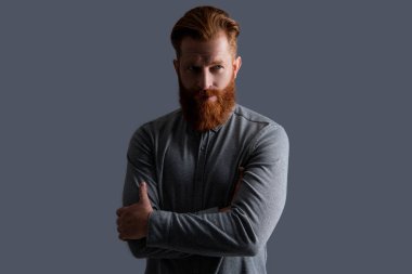 Kollarını kavuşturan kendine güvenen sakallı adam. Kızıl sakallı ve bıyıklı İrlandalı bir adam. Ciddi traşsız adam stüdyosu Griler 'de izole edilmiş..