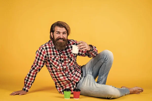 Mutlu, sakallı, sakalsız, şık saçlı, sıradan kıyafetler giyen, kahve içen, enerjik bir adam..