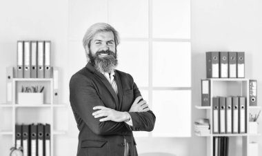 Özsaygı duygusu. Modern ofiste mutlu bir girişimci. İş başarısı. Ceketli başarılı sakallı CEO. Kendine güvenen bir yönetici, bir işyeri. Olgun erkek patron. Elleri çapraz iş adamı.