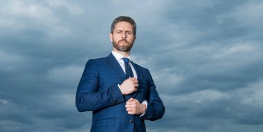 İşadamı gökyüzü arka planının portresi. Takım elbiseli bir iş adamı. Ciddi, kır saçlı iş adamı..