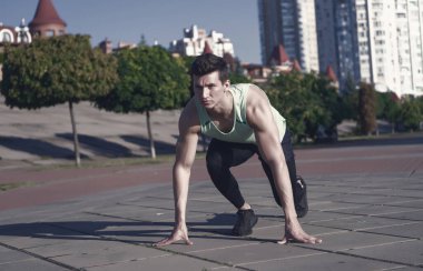 Maço eşofman ve spor ayakkabısı içinde kentsel peyzaj uygun. Hazır sabit git. Sağlıklı yaşam konsepti. Başlama pozisyonu, adam atlet. Güneşli yaz gün açık havada yolda asfalt atlet.