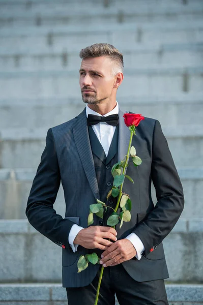 special occasion concept. grizzled man with rose for special occasion. tuxedo man outdoor at special occasion.