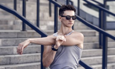 Kolunu esneten bir sporcu. Sporcuların ısınma turları. Isınma ve esneme hareketleri. Sporcu adam antrenmandan önce ısınıyor..