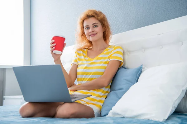 communication of happy woman with coffee and laptop. online communication of woman at home. laptop communication of woman in bed with coffee.