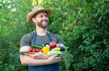 Hasır şapkalı çiftçi taze olgun sebzeleri tutuyor..