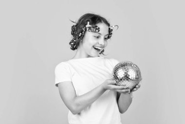 Hadi retro partisinde eğlenelim. Disko topu dekorasyonu. Disko topu olan güzel bir kız. Moda kızı sarı arka planda bigudilerle poz veriyor. Cumartesi gecesi ve disko balosu. Bebek partisi. Mutlu Noeller..