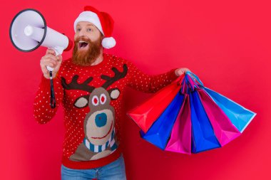 Sakallı Noel Baba elinde alışveriş torbalarıyla hoparlöre bağırıyor. Mutlu adam tatil indirimi duyurusu yapıyor. Noel indirimi duyurusu. Dükkan duyurusu. Mutlu noeller. Mutlu yıllar..