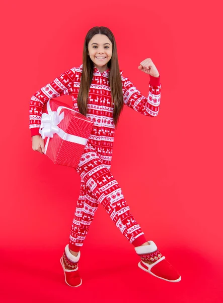 Mutlu noeller. Stüdyoda kırmızı Noel hediyeli mutlu genç kız. Genç kız Noel hediyesini kırmızı arka planda tek başına duruyor..
