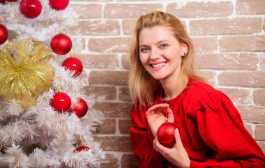 Neşeli bir kadın Noel ağacının yanında dinleniyor. Tatil kutlamaları başlamadan önce yapman gereken şeyler. Noel arifesi kavramı. Elbiseli kız Noel ağacını süslerle süslüyor. Noel 'i bekliyorum.