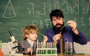 Sakallı öğretmen ve küçük çocuk. baba ve oğul okulda. Renkli sıvı kimya deneyiyle laboratuvar test tüpleri ve mataralar. Laboratuvar araştırma ve geliştirme. Tabanı bırakın..
